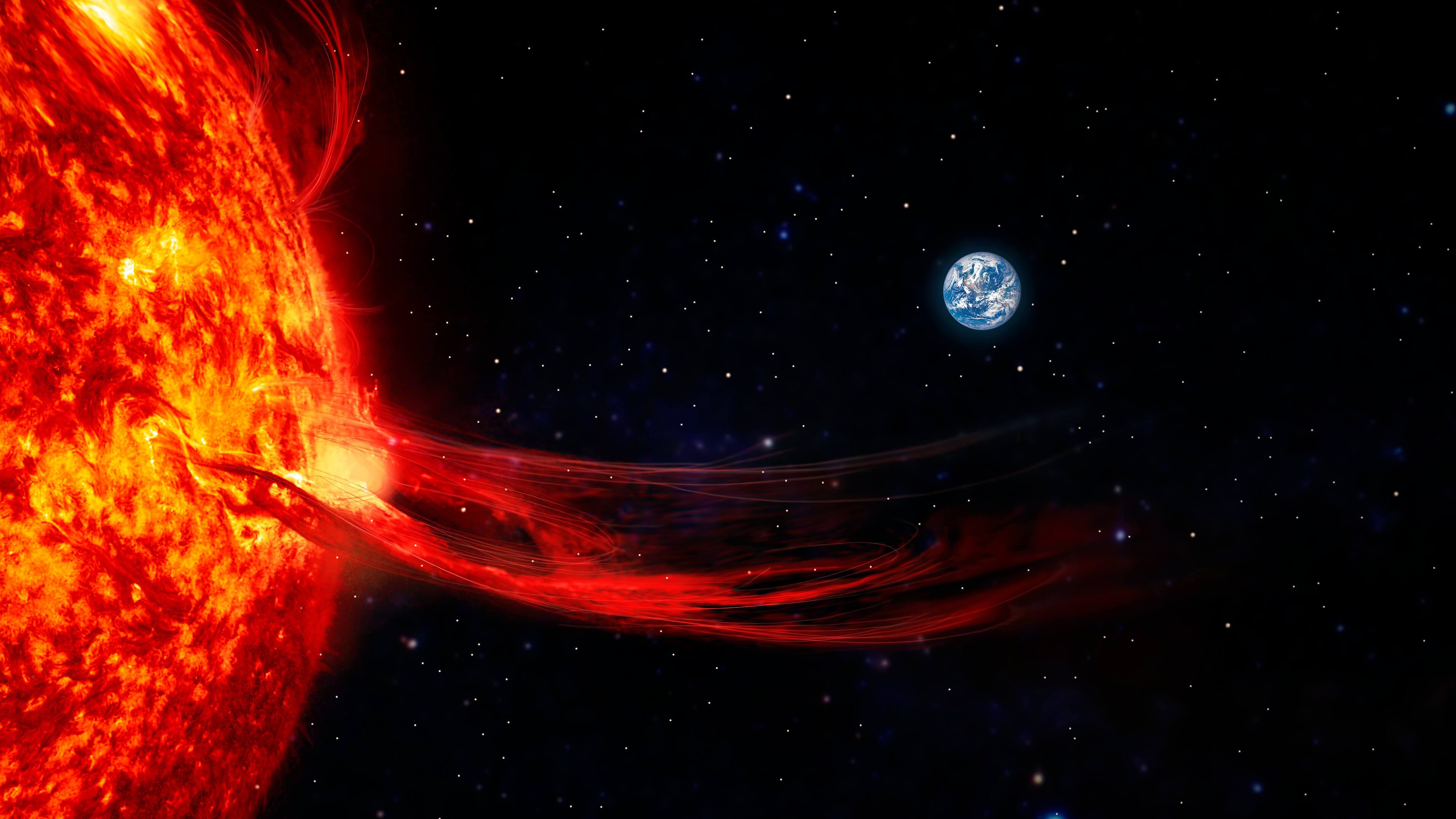 Une éruption solaire à la surface du Soleil s’étend dans l’espace, la Terre étant visible au loin sur fond d’étoiles.